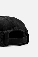 Hat made of tonal matching fabrics with turned-up knit brim. Adjusts with loop.