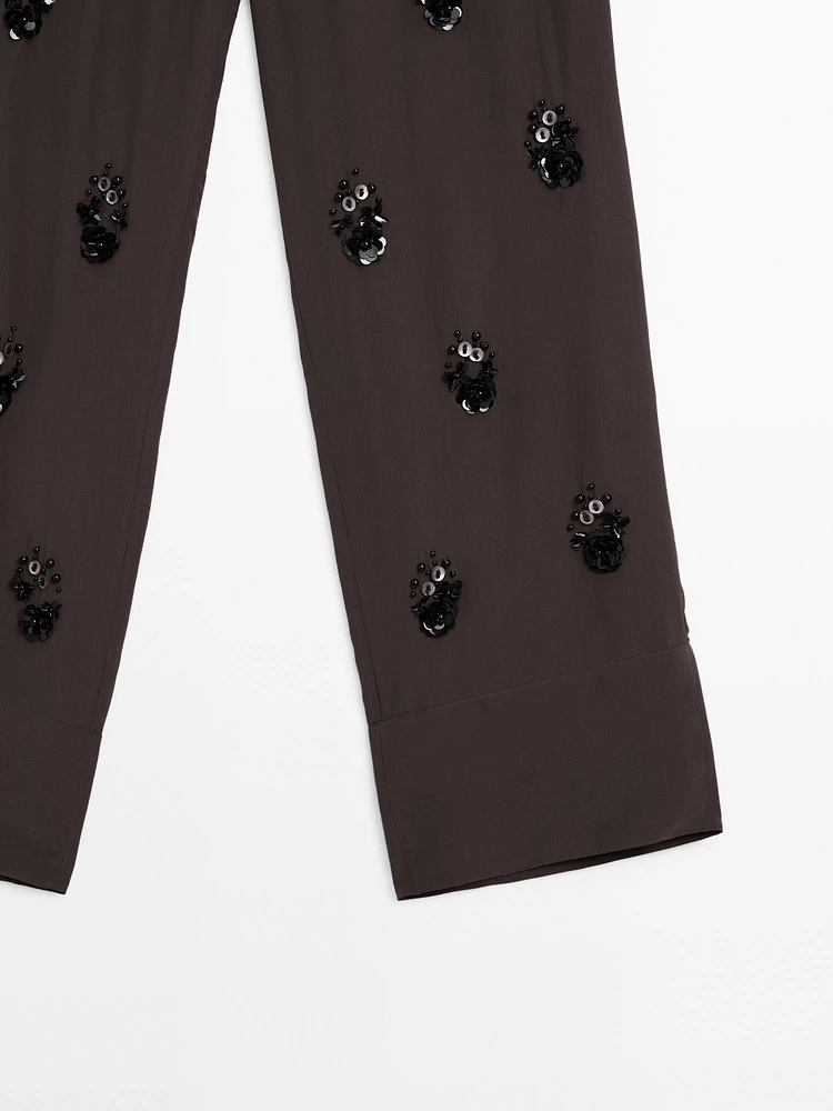 Flowing trousers with floral appliqués