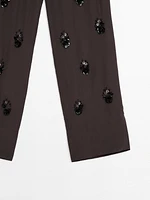Flowing trousers with floral appliqués
