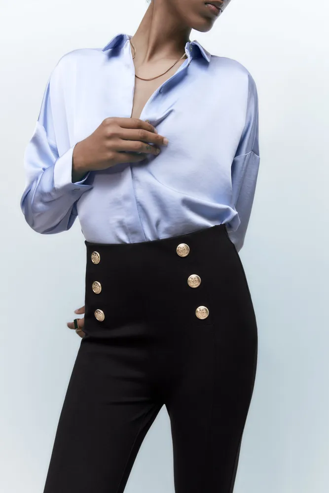 High-waisted leggings with elastic waistband. Front gold false buttons.