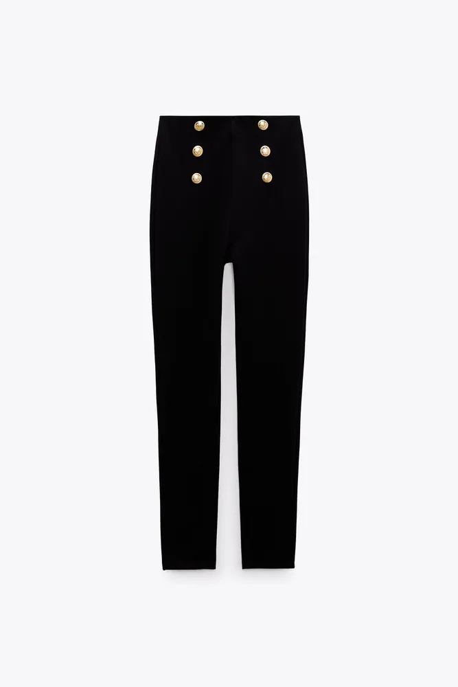 High-waisted leggings with elastic waistband. Front gold false buttons.