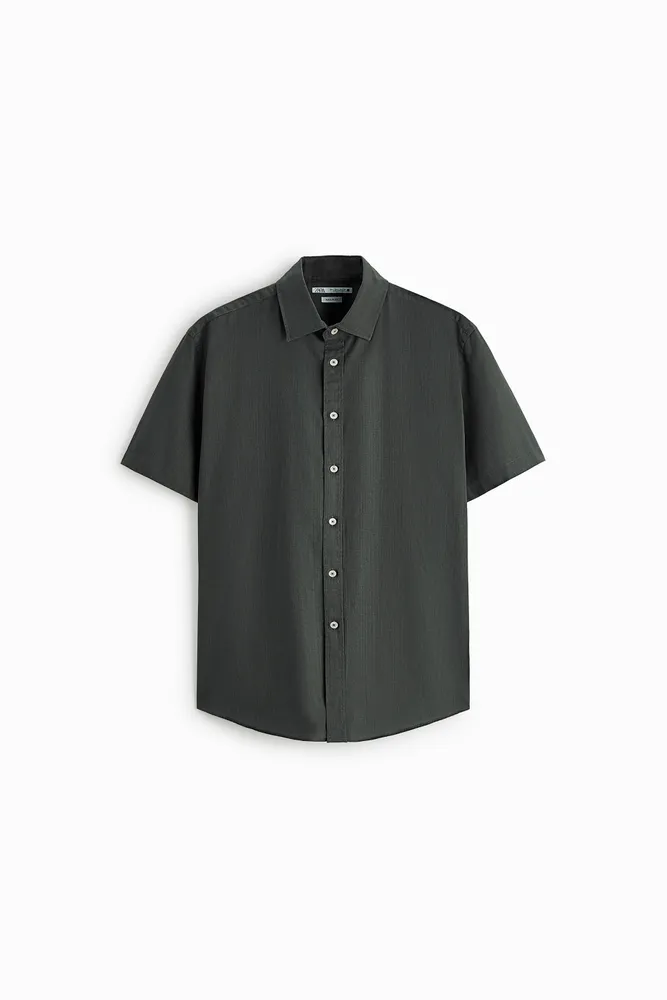Shirt made of uneven textured cotton fabric. Lapel collar and short sleeves. Front button closure.