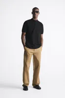 Band collar shirt with front button closure and short sleeves. Side vents at hem.