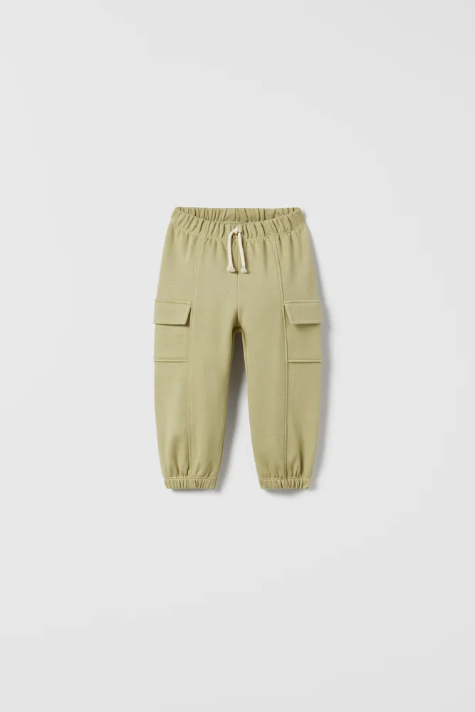 Cargo pants with Elastic waistband and front drawstring appliqué. Pockets at sides flaps. cuffs.