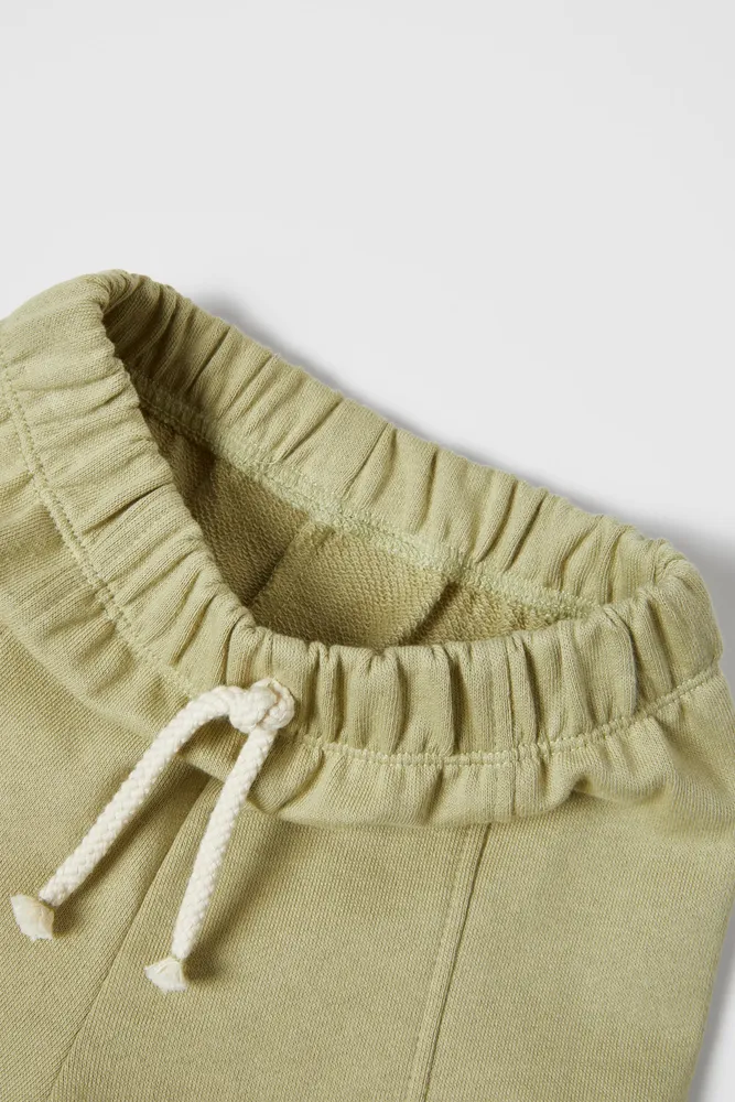 Cargo pants with Elastic waistband and front drawstring appliqué. Pockets at sides flaps. cuffs.