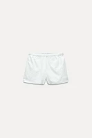 Shorts with a mid elastic waistband. Side hidden in-seam pockets. Tonal embroidery.