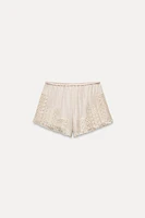 Shorts made of 100% viscose. Mid-rise elastic waistband. Matching lace appliqué.