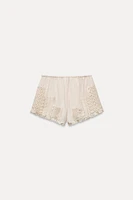 Shorts made of 100% viscose. Mid-rise elastic waistband. Matching lace appliqué.