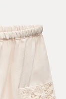 Shorts made of 100% viscose. Mid-rise elastic waistband. Matching lace appliqué.