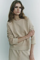 Sweatshirt made of spun cotton blend fabric. Round neck and long raglan sleeves. Tonal rib trim