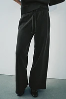 Pants made of a cotton blend. Mid waist and adjustable elastic drawstring waistband. Side pockets. Wide leg.