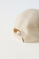 Hat with adjustable adhesive strap at nape.