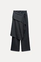 Pants made of 100% cotton. Mid-rise elastic waist. Overlapping wrap front with self-tie fastening at side.