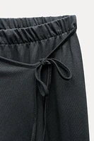 Pants made of 100% cotton. Mid-rise elastic waist. Overlapping wrap front with self-tie fastening at side.