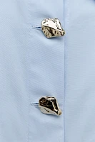 Shirt with lapel collar and long sleeves. Front closure hidden buttons embossed gold buttons.