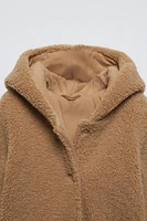 Faux shearling bodysuit with hood and long sleeves. Snap button closure front patch pockets.Interior lining.