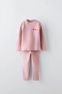 Two-piece matching set. T-shirt with round neck and long sleeves. Embroidery detail at chest. Leggings elastic waistband.