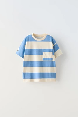 Round neck T-shirt with short sleeves. Patch pocket at chest. Label appliqué sleeve.