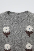 Knit sweater with round neck and long sleeves. Embroidered flower detail on front