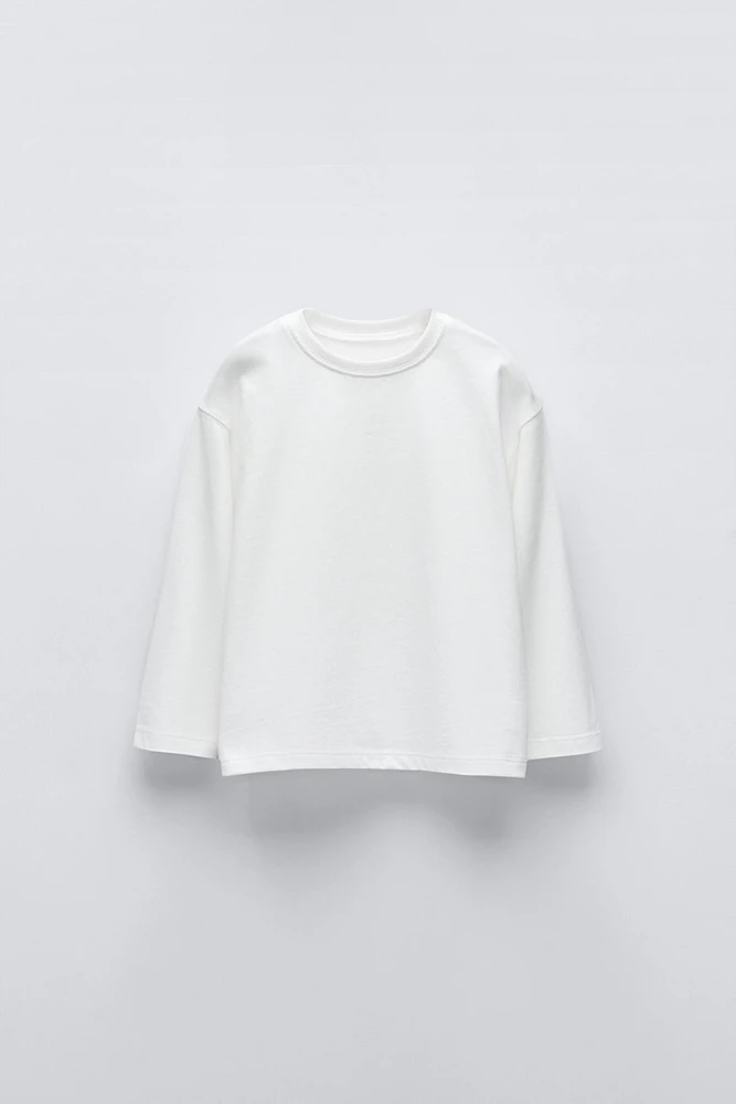 T-shirt with round neck and long sleeves. Label appliqué at back hem.
