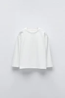 T-shirt with round neck and long sleeves. Label appliqué at back hem.