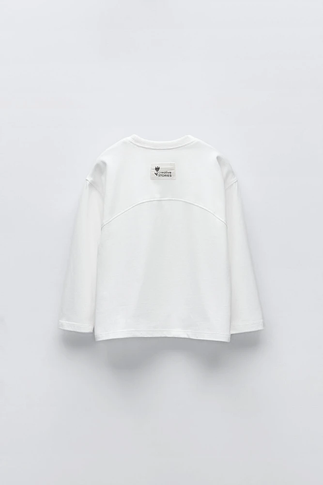 T-shirt with round neck and long sleeves. Label appliqué at back hem.