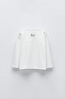 T-shirt with round neck and long sleeves. Label appliqué at back hem.