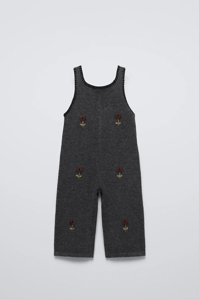 Sleeveless knit overalls with round neckline. Front floral embroidered detail.