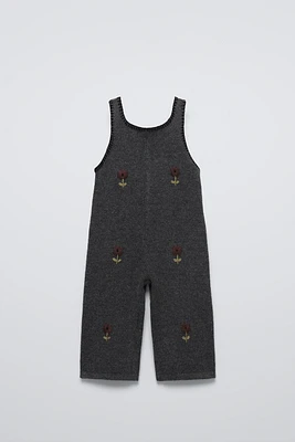 Sleeveless knit overalls with round neckline. Front floral embroidered detail.