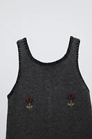 Sleeveless knit overalls with round neckline. Front floral embroidered detail.