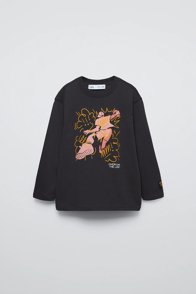 Round neck shirt with long sleeves. Front graffiti print. Label appliqué at sleeve.