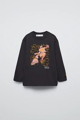 Round neck shirt with long sleeves. Front graffiti print. Label appliqué at sleeve.