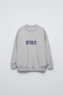 Round neck sweatshirt with long sleeves. Rib trim. Text print at chest and sleeve embroidery detail.