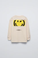 Crew neck T-shirt. Cuffed long sleeves. Smileyworld ® print at front and back. Label appliqué hem.