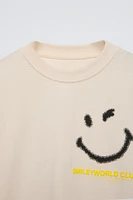 Crew neck T-shirt. Cuffed long sleeves. Smileyworld ® print at front and back. Label appliqué hem.