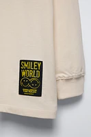 Crew neck T-shirt. Cuffed long sleeves. Smileyworld ® print at front and back. Label appliqué hem.