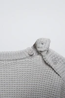 Sweater with round neck and long sleeves cuffs. Back button closure. Patch pocket at chest. Label appliqué hem.