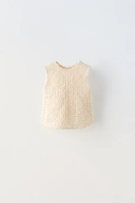 Sleeveless round neck knit top. Buttoned teardrop closure at back.