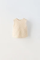 Sleeveless round neck knit top. Buttoned teardrop closure at back.