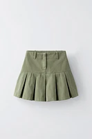 Skirt with interior adjustable waistband and side zip closure. Box pleats at hem.