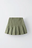 Skirt with interior adjustable waistband and side zip closure. Box pleats at hem.