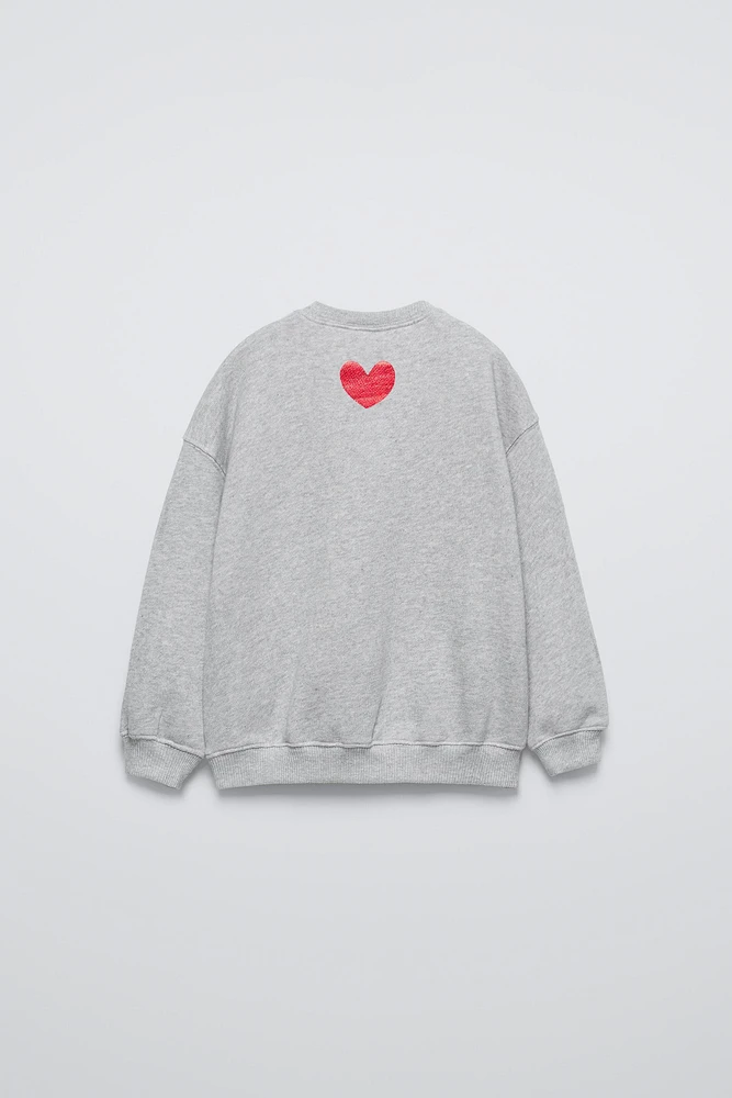 Round neck sweatshirt with long sleeves. Rib trim. Shiny slogan print on the front. Warm and soft feel interior fabric.