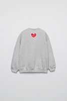 Round neck sweatshirt with long sleeves. Rib trim. Shiny slogan print on the front. Warm and soft feel interior fabric.