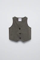 Sleeveless V-neck vest. Front button closure and back appliqué.