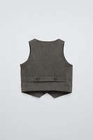 Sleeveless V-neck vest. Front button closure and back appliqué.