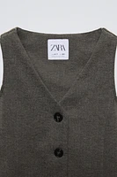 Sleeveless V-neck vest. Front button closure and back appliqué.