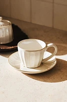 STONEWARE TEACUP AND SAUCER WITH RAISED DESIGN