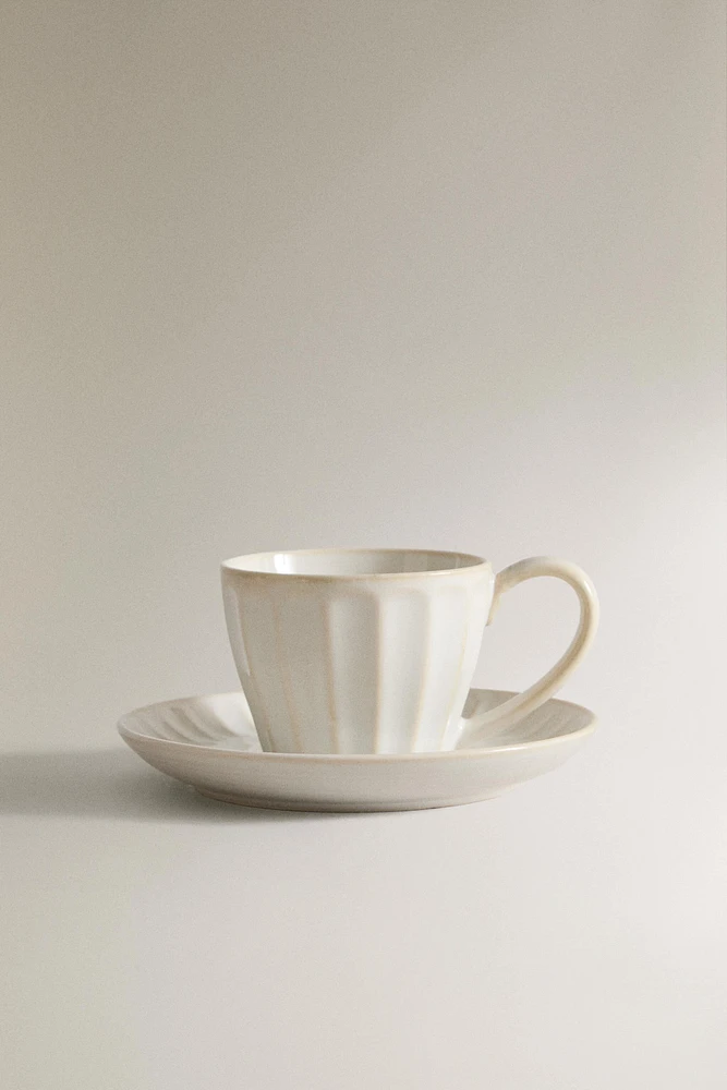 STONEWARE TEACUP AND SAUCER WITH RAISED DESIGN