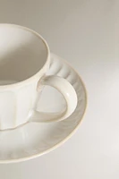 STONEWARE TEACUP AND SAUCER WITH RAISED DESIGN