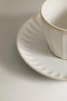 STONEWARE TEACUP AND SAUCER WITH RAISED DESIGN